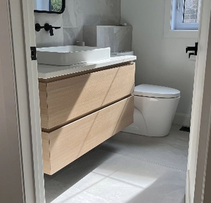 Bathroom with large-format ceramic tiles and a light wood vanity